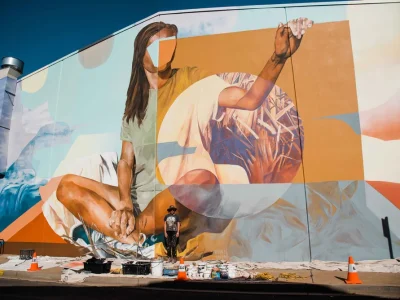A large, colourful outdoor mural depicting a woman in a seated