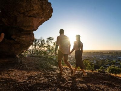 A silhouette of a couple walking hand-in-hand toward a golden sunset