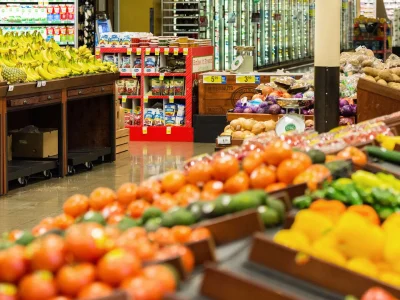 A vibrant grocery store produce section featuring rows of fresh tomatoes and bell peppers in the foreground