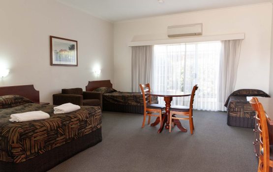 A spacious motel room with one double bed and two single beds