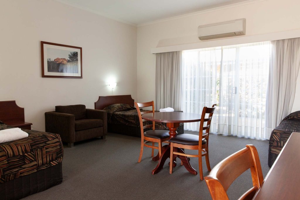 A spacious motel room featuring multiple beds with patterned bedspreads
