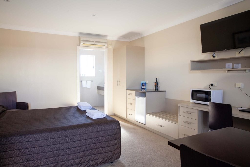 The Kidman Wayside Inn room featuring a large bed with a dark brown textured coverlet