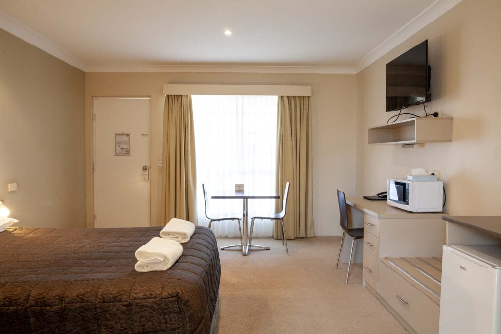 The Kidman Wayside Inn bed with a dark textured coverlet and folded white towels.