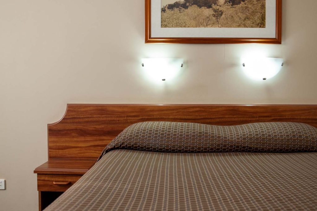 A hotel-style bed with a brown patterned bedspread and white towel