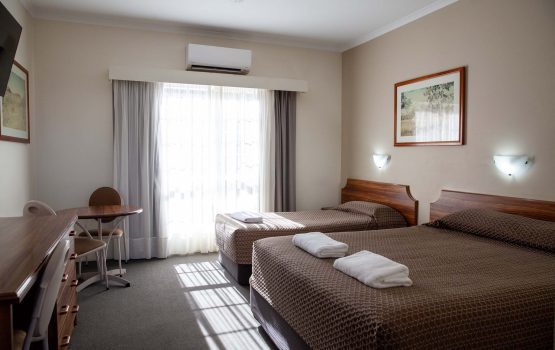 The Kidman Wayside Inn two beds covered in patterned brown bedspreads and a small dining table with chairs
